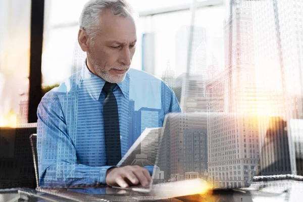 Ernsthafter reifer Mann schaut sich die Dokumente während der Arbeit an — Stockfoto