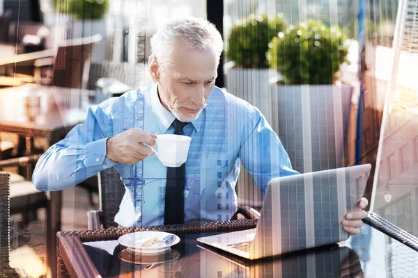 Συμπυκνωμένο ώριμος άνδρας, πίνοντας καφέ και κοιτάζοντας την οθόνη — Φωτογραφία Αρχείου