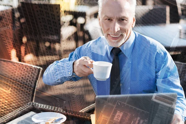 Volwassen man glimlachend en koffie drinken in een leuk café — Stockfoto