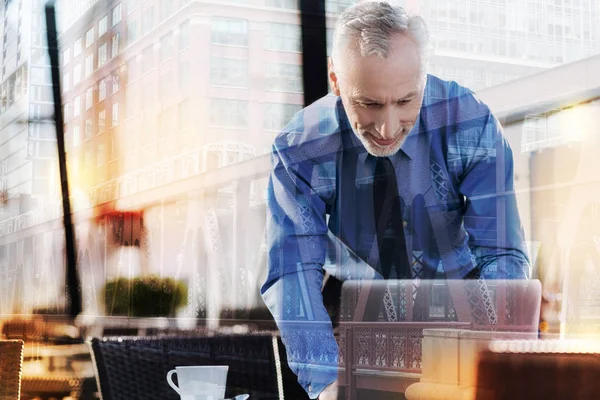 Mosolygó ember hajol a laptop, miközben egy kávézóban — Stock Fotó