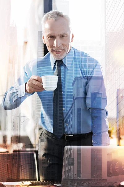 Knappe rijpe zakenman drinken van zijn koffie en glimlachen — Stockfoto