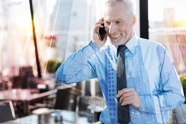 Emotional mature man smiling while talking on the phone