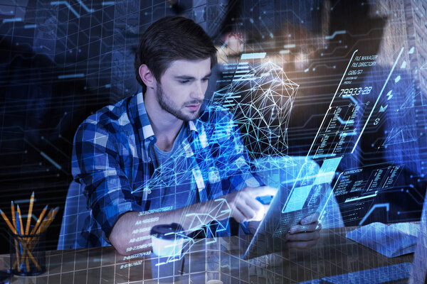 Smart programmer looking at his tablet while sitting in his office alone
