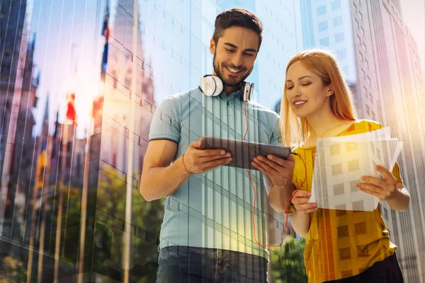 Joven sonriendo mientras muestra su tableta a un compañero de estudios amigable — Foto de Stock