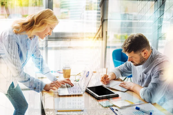 Jonge man maken van notities terwijl zijn collega werken op de laptop — Stockfoto