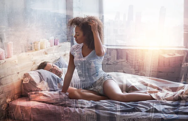 Aantrekkelijke jonge vrouw zittend op het bed — Stockfoto