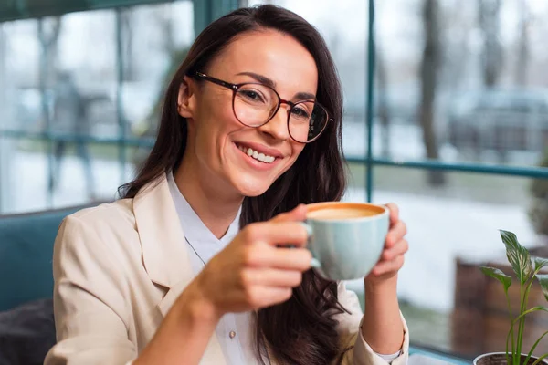 Радостная веселая женщина, потягивающая кофе — стоковое фото