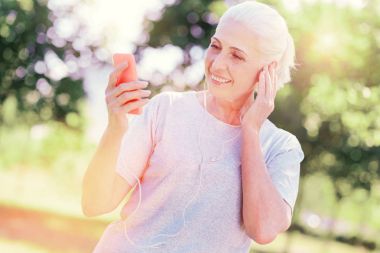 Cep telefonu kullaranarak memnun yaşlı kadın