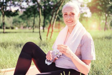 Bir şişe su ile gülümseyen yaşlı kadın