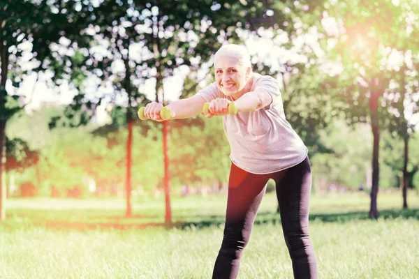 Excited elderly woman using weights