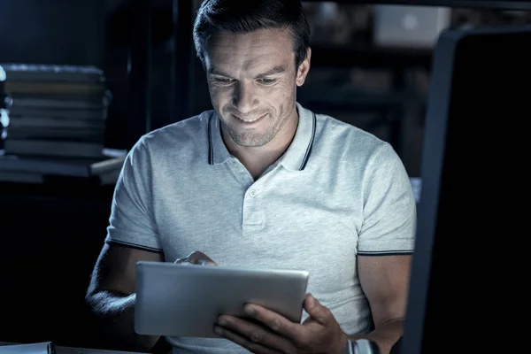 Vrolijke duizendjarige man die lacht tijdens het werken aan touchpad — Stockfoto