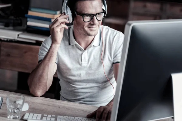 Uśmiechający się dojrzały mężczyzna, słuchanie muzyki podczas pracy na komputerze — Zdjęcie stockowe