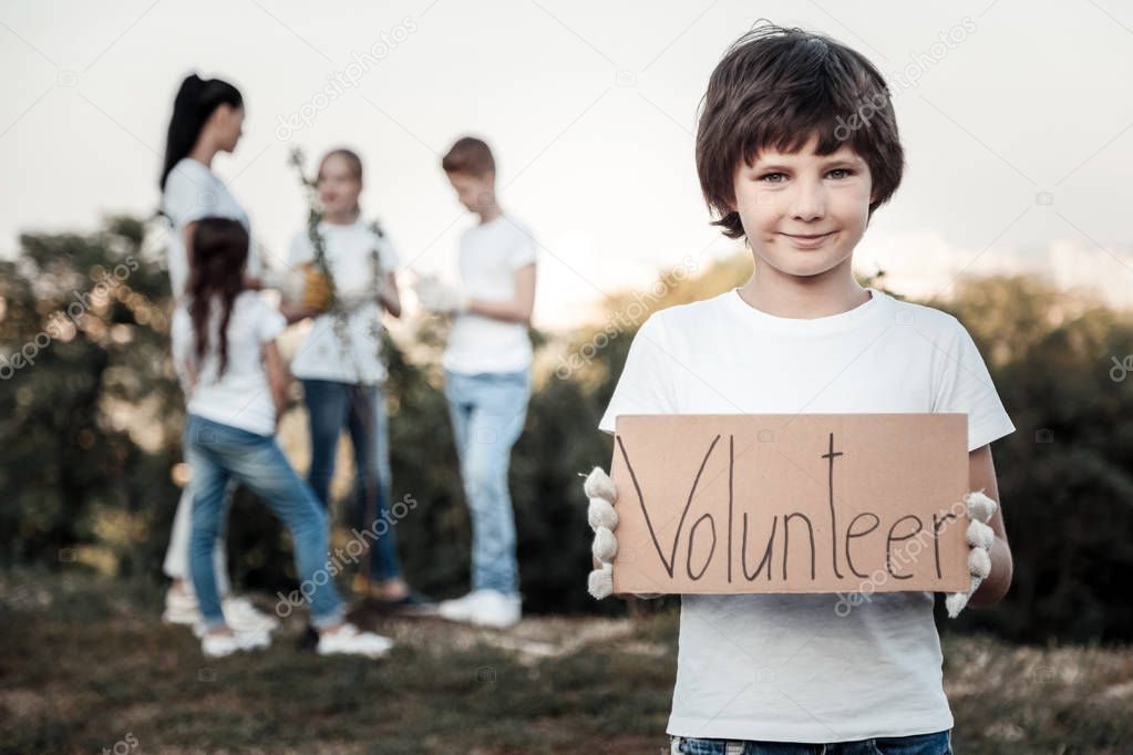 Cheerful nice boy being a volunteer
