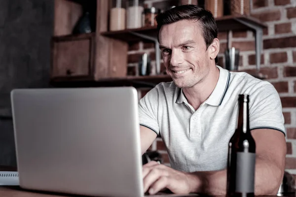Sorrindo homem usando laptop e bebendo veados — Fotografia de Stock