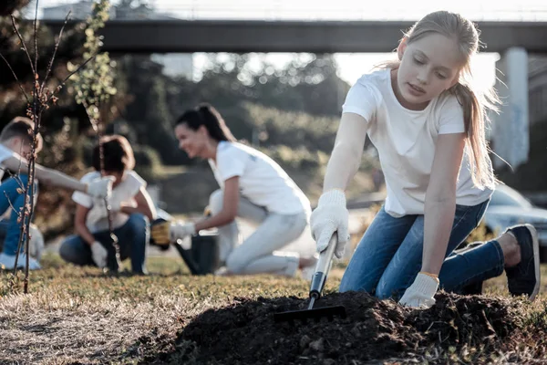 Hübsches blondes Mädchen, das mit einer Harke arbeitet — Stockfoto