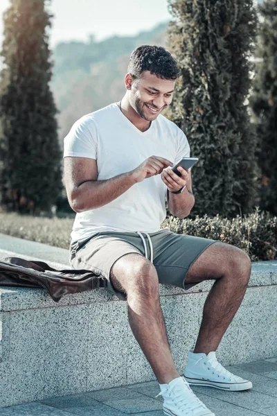 Hombre agradable alegre mirando la pantalla de su teléfono inteligente —  Fotos de Stock