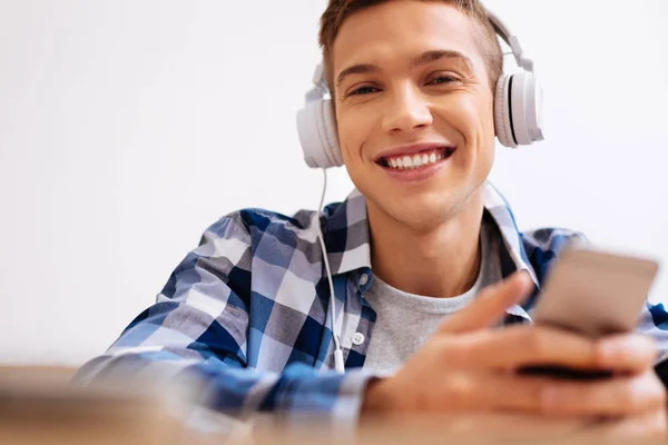 Glücklicher Junge trägt Kopfhörer und benutzt sein Handy — Stockfoto