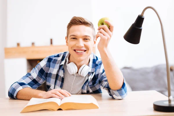 Happy teenager sitting at the table with an apple — Stock Photo, Image