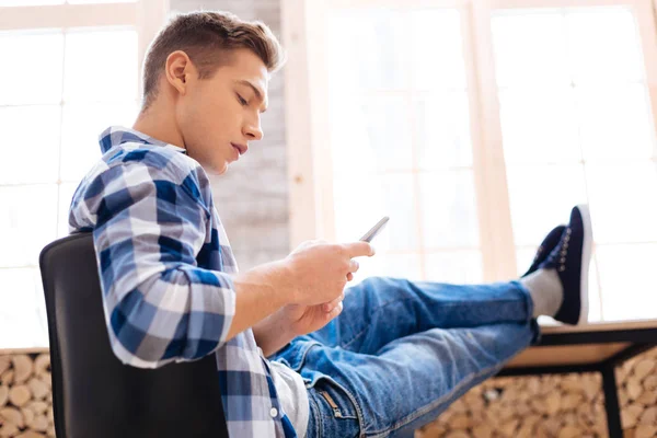 Determined unsmiling teenager using his phone — Stock Photo, Image