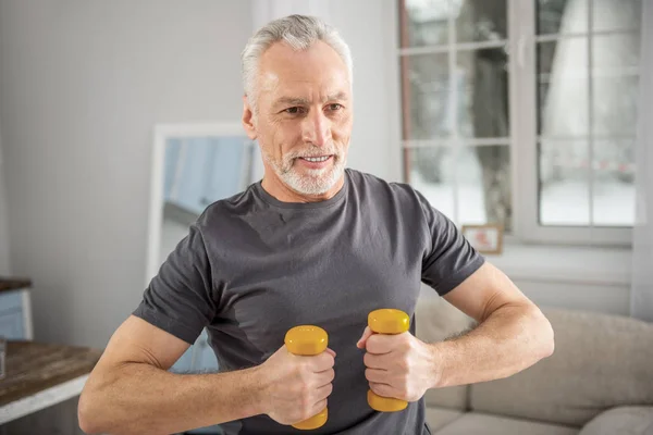 Concentrated bearded male holding dumbbells — Stock Photo, Image