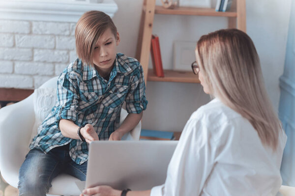 Nervous boy pointing at laptop in psychologist office