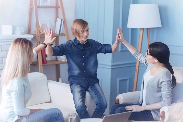 Cheerful child pressing palms together with mom and therapist — Stock Photo, Image