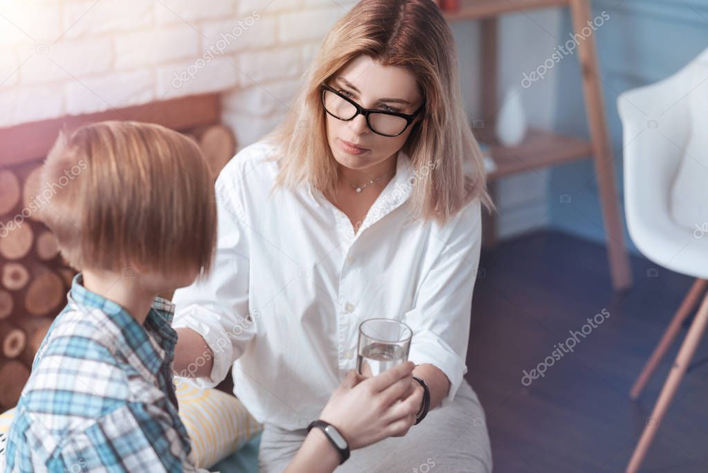 Female psychologist giving glass of water to child patient
