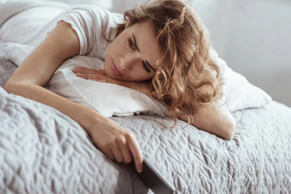 Mujer deprimida que tiene pensamientos negativos mientras está acostada en la cama —  Fotos de Stock