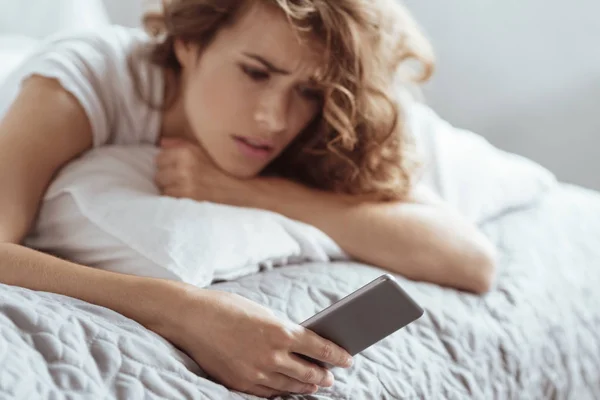 Worried woman thinking about something while holding her smartphone — Stock Photo, Image