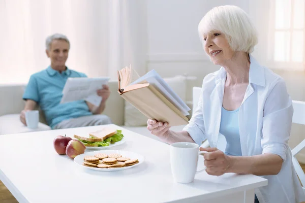 Cheerful nice pensioner reading a book — Stock Photo, Image