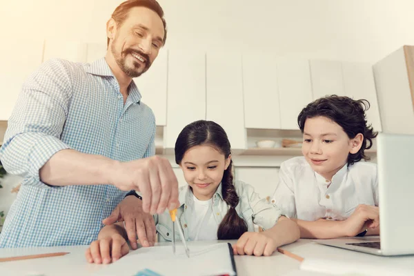 Счастливый умный человек помогает своим детям с домашним заданием — стоковое фото