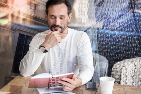 Junger Mann revidiert seine Notizen, während er im Café sitzt — Stockfoto