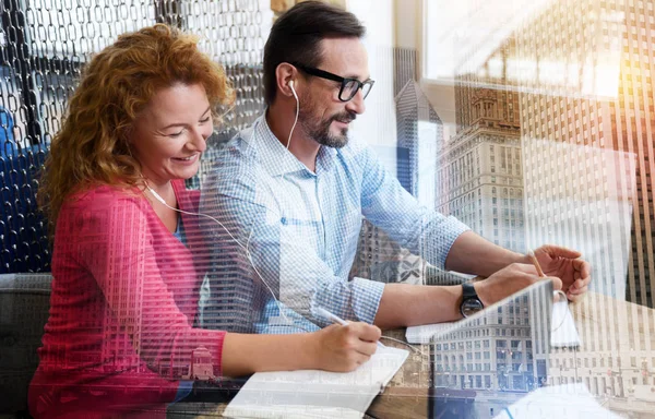 Vrolijke collega's luisteren naar muziek in één paar oortelefoons — Stockfoto