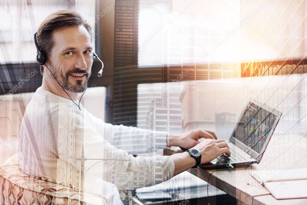 Pleasant man in headset posing while creating a presentation