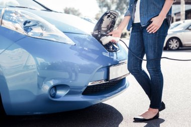 Genç akıllı kadın ayakta ve şarj Gadget'ı kullanma.