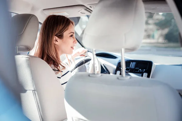 Concentrado mulher bonito sentado no carro e olhando para o lado . — Fotografia de Stock