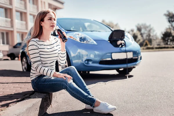 Beautiful pretty woman drinking cola and charging the car. — Stock Photo, Image