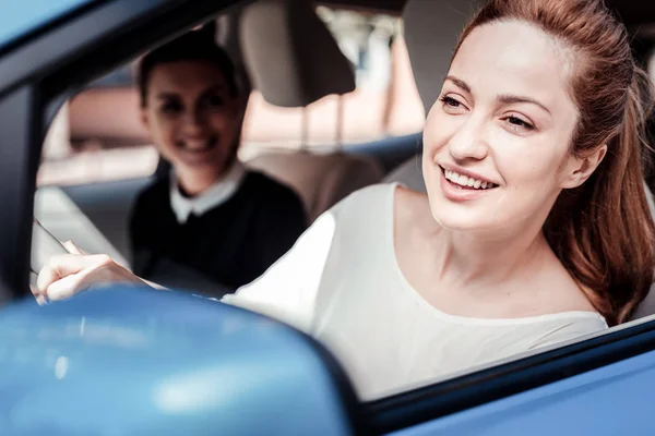 Gioiosa donna elegante che guarda sulla strada seduta in auto . — Foto Stock