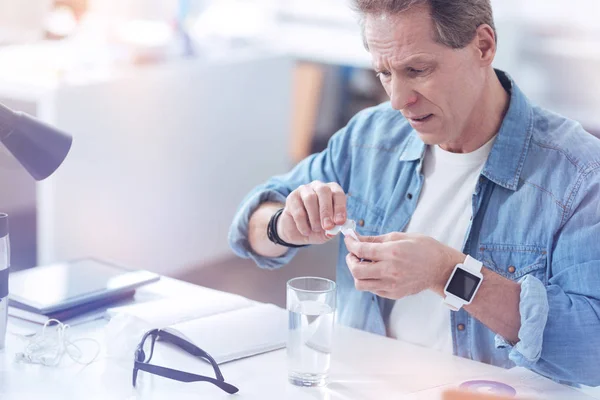 Sorgliga glädjelös man förbereder sig för att ta sin medicin — Stockfoto