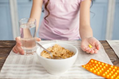 Bir bardak su ve vitamin tutan küçük kız