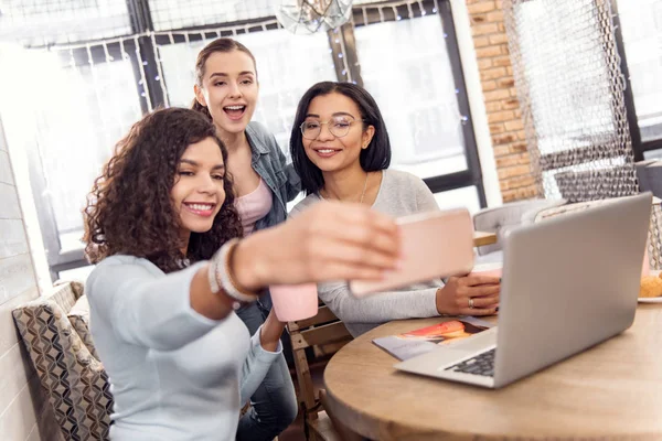 Jowialny trzech uczniów biorąc selfie podczas studiów — Zdjęcie stockowe