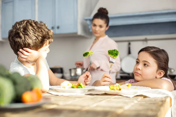 Bister flicka och hennes bror att ha grönsaker till frukost — Stockfoto