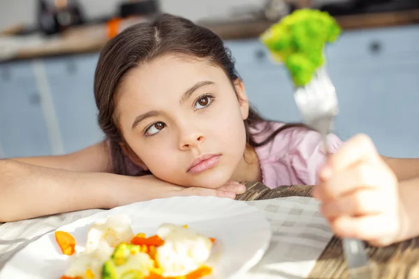 Aufgebrachtes Kind blickt auf das Gemüse auf der Gabel — Stockfoto