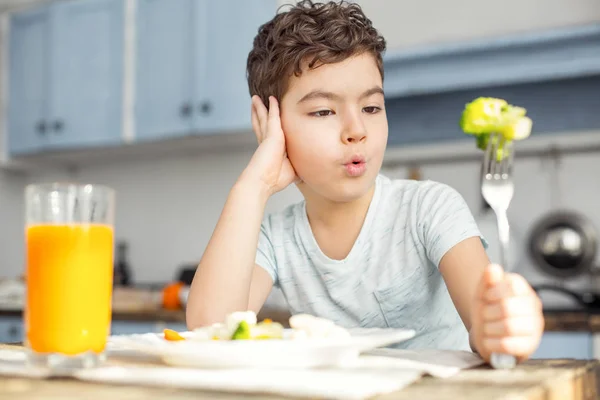 Triste menino comendo legumes para o café da manhã — Fotografia de Stock