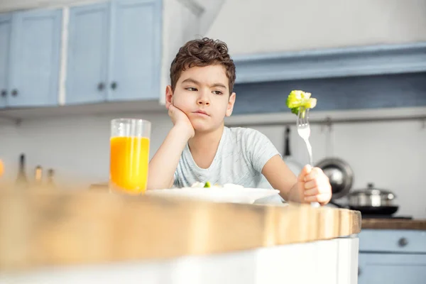Неулыбчивый мальчик ест овощи на завтрак — стоковое фото