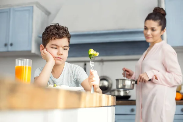 Boldogtalan fiú, íztelen zöldségek eszik reggelire — Stock Fotó