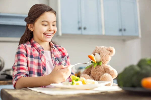 Menina inspirada alimentando seu brinquedo com alimentos saudáveis — Fotografia de Stock