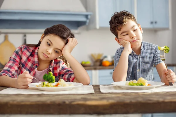 Нещасливі брати і сестри дивляться сумно на овочі — стокове фото