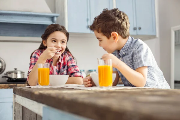 Menina encantada olhando para seu irmão e comer — Fotografia de Stock