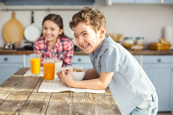 Zufriedener kleiner Junge frühstückt mit seiner Schwester — Stockfoto